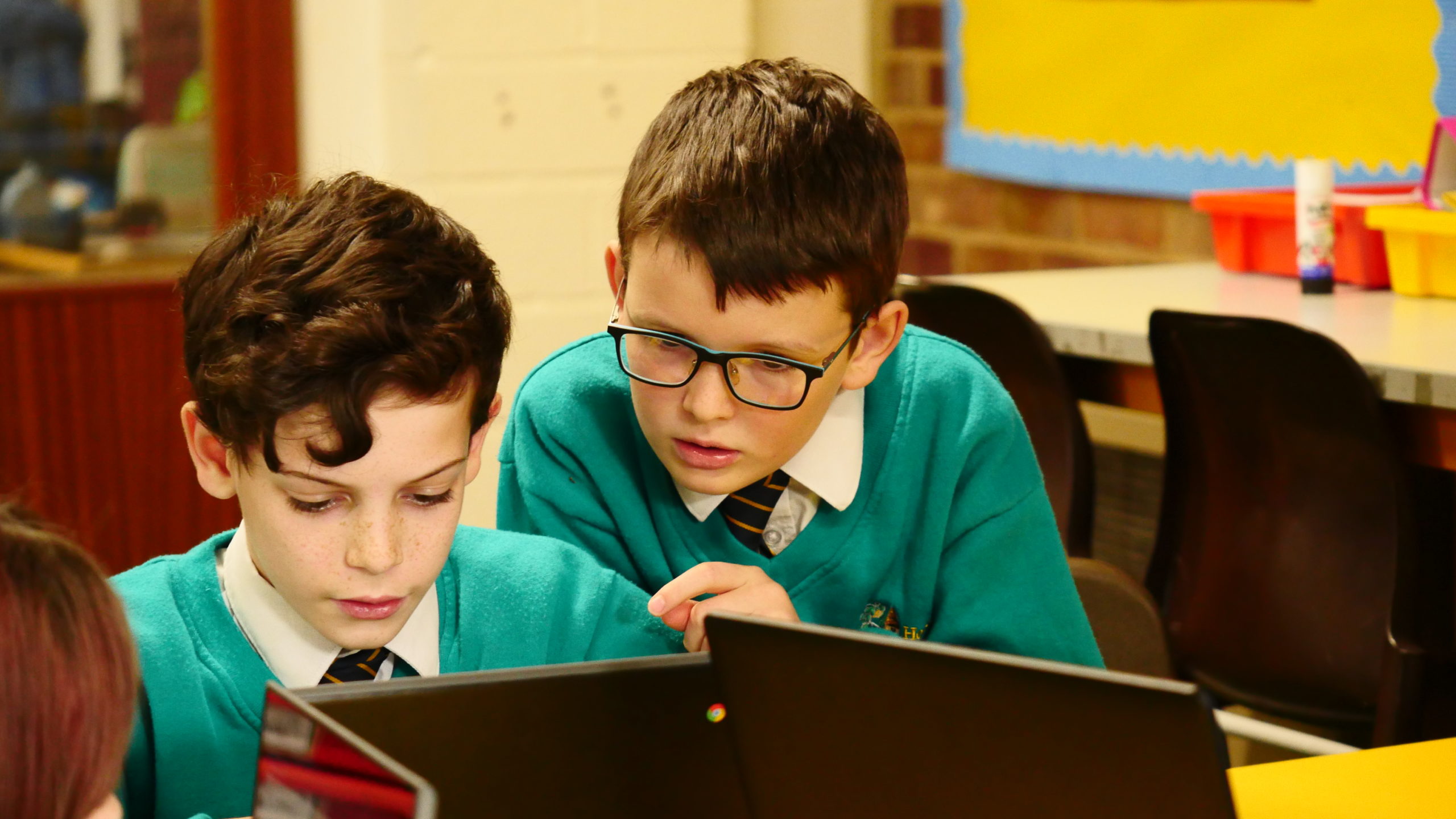 Two boys looking at a computer screen in a classroom.