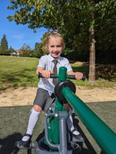 A young girl can be seen using one of the outdoor Gym apparatus on the academy grounds and smiling for the camera.