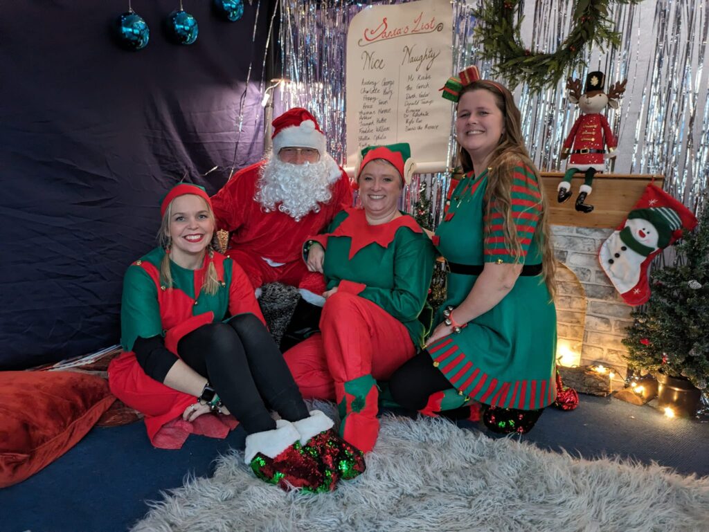 Photo of four members of staff dressed up as Santa Claus and his Elves in a Grotto for the students to visit.