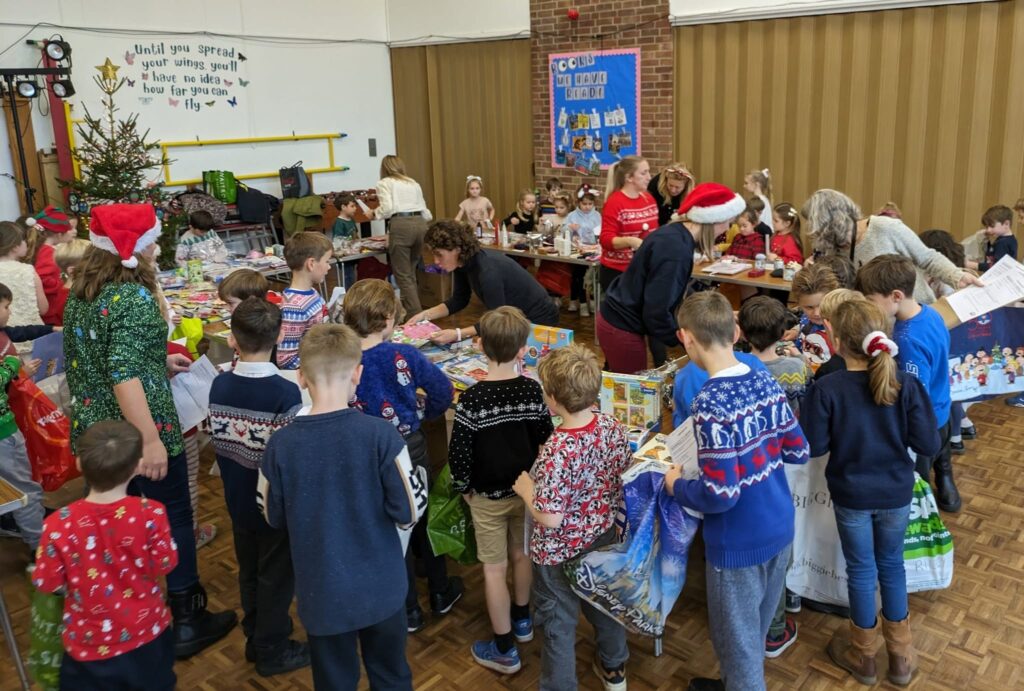 A large group of pupils are pictured visiting a Christmas market being run by staff in the main hall in the academy building.
