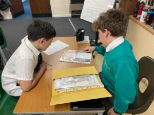Two pupils boys are pictured sat together at a desk, looking at some memorabilia from WWII.