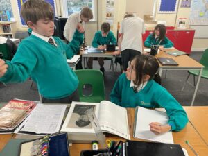 Two pupils are pictured looking at some photos and documents from WWII and conversing with one another.