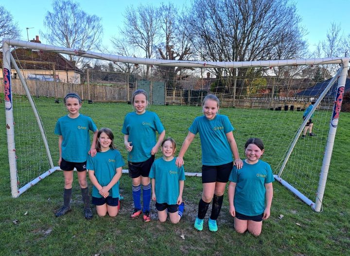 Six Year 5 students are pictured smiling, whilst posing for a group photo together under a goalpost.