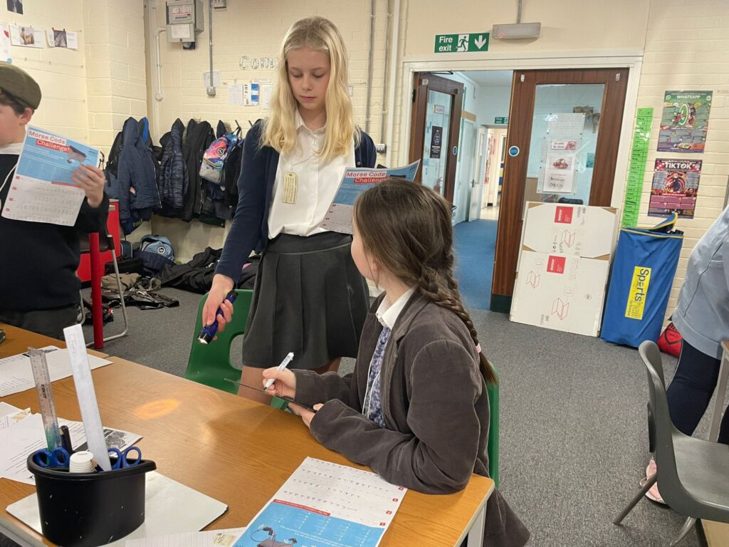 Two female Year 6 students, dressed as WWII evacuees, are seen learning about the era.