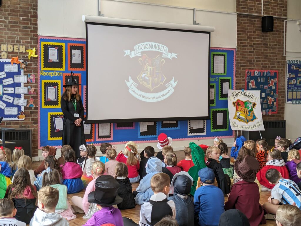 A large group of students are pictured dressed up as well-known characters from books for World Book Day 2024 and sitting in the main hall.